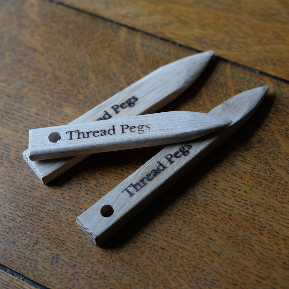 Wooden point turner with 'Thread Pegs' engraving on a wooden surface