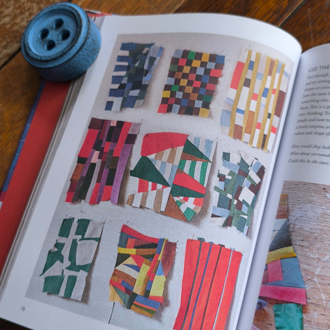 Book open to fabric swatches with a blue button on a wooden surface