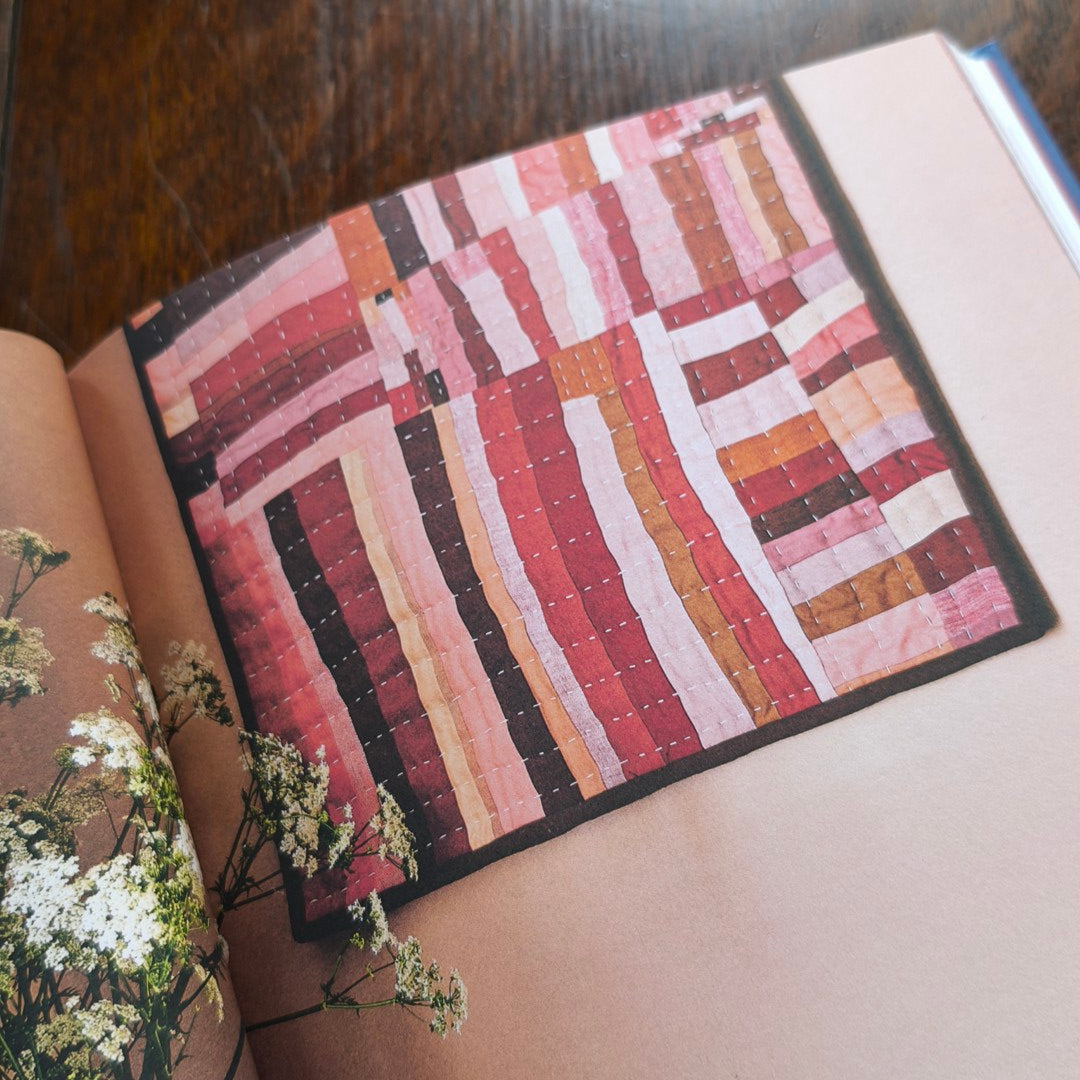 Quilted wall hanging with geometric pattern in a book on a wooden surface