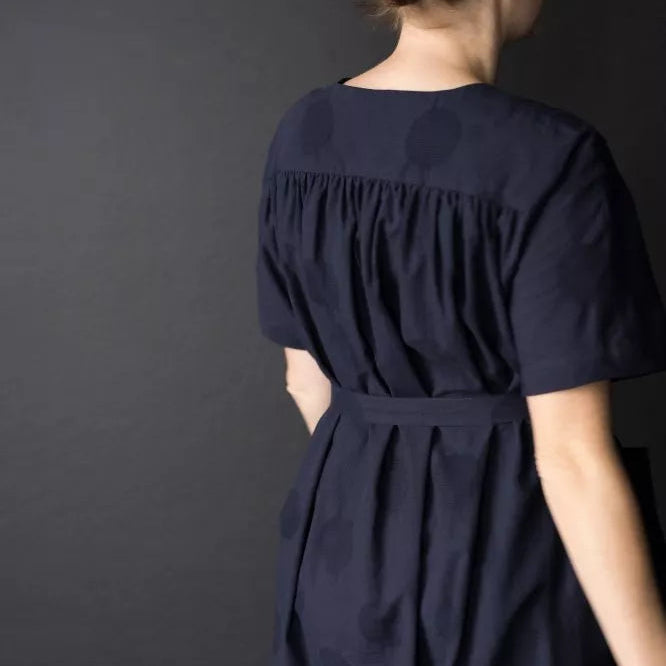 Navy blue dress worn by a person against a dark background