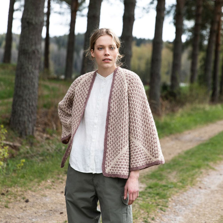 Person wearing a patterned cape in a forest setting