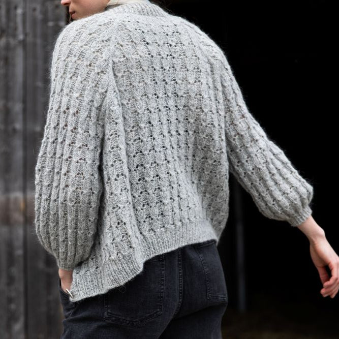 Person wearing a textured gray sweater against a dark background