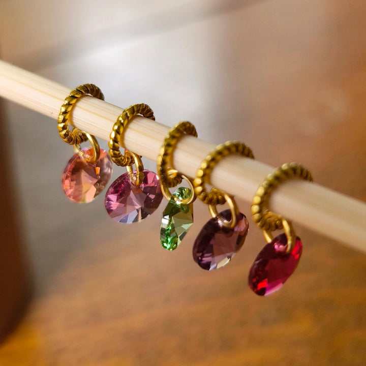 Colorful crystal charms stitch markers on a wooden knitting needle