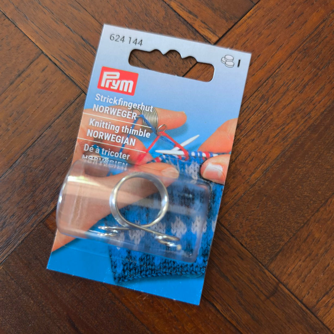 Knitting thimble in packaging on a wooden surface